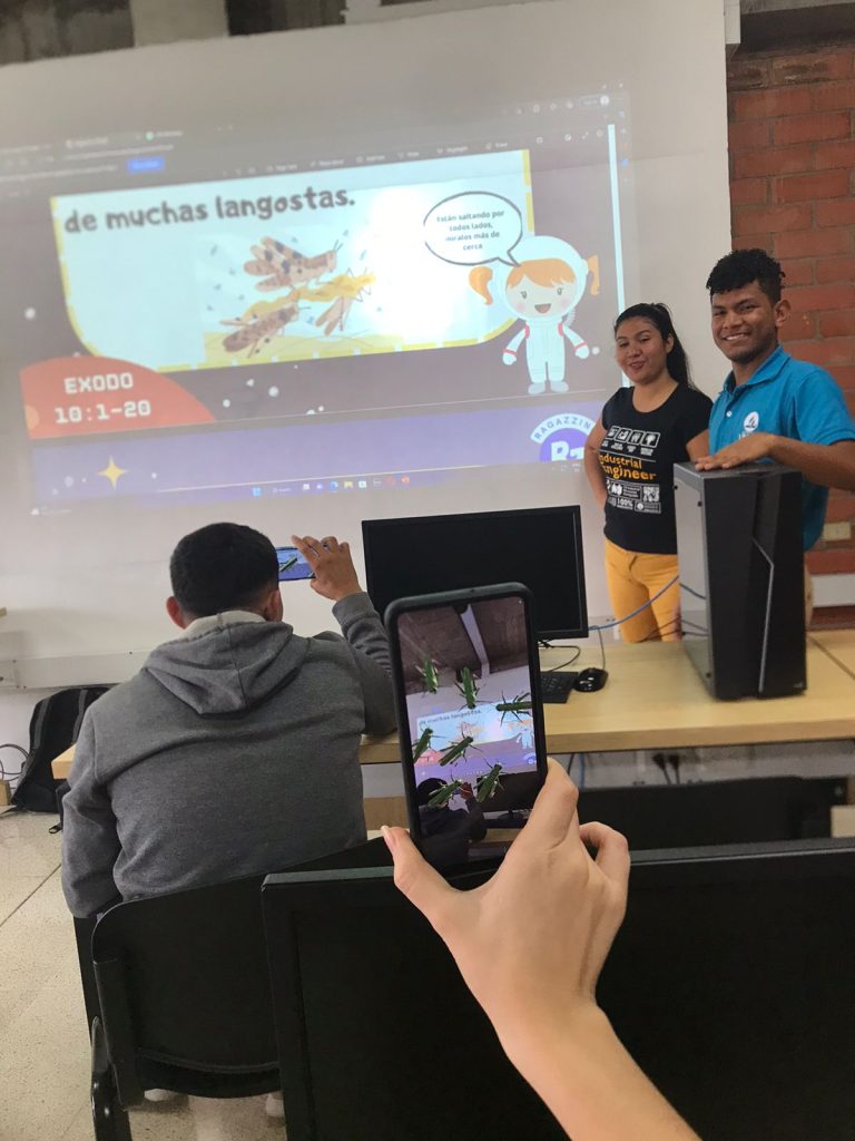 Telefono desplegando elementos de realidad aumentada presentes en el tablero del laboratorio de análisis de datos y simulación financiera de la Corporación universitaria adventista 