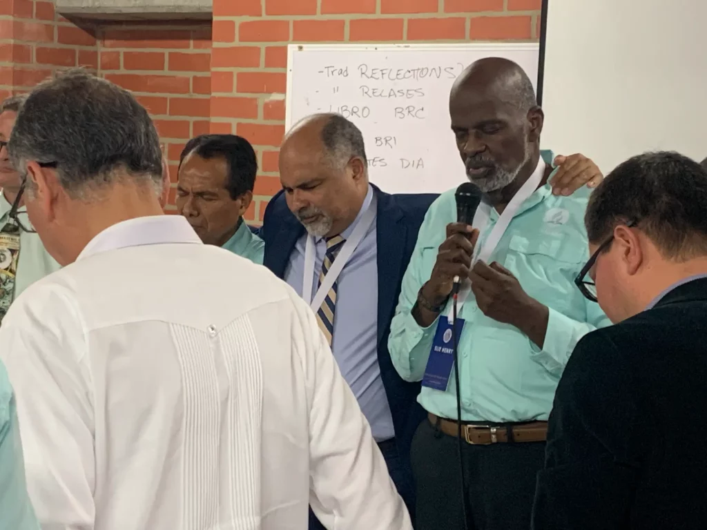 Presidente de la DIA Elie Henry orando con los integrantes al evento del comite de investigacion biblica